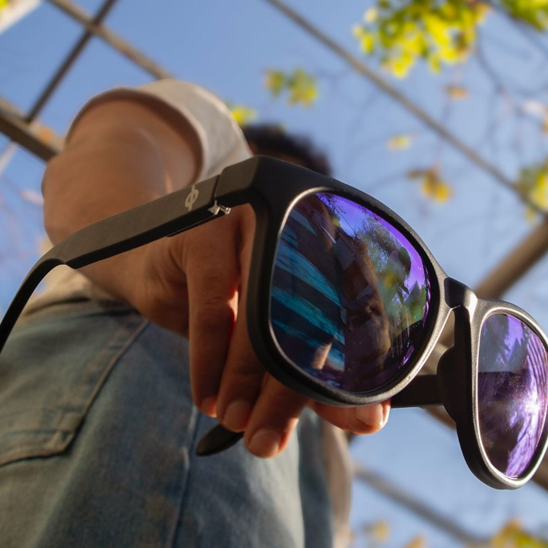 A creative composition featuring the "First Lens" sunglasses against a vibrant background, highlighting their versatility and style.