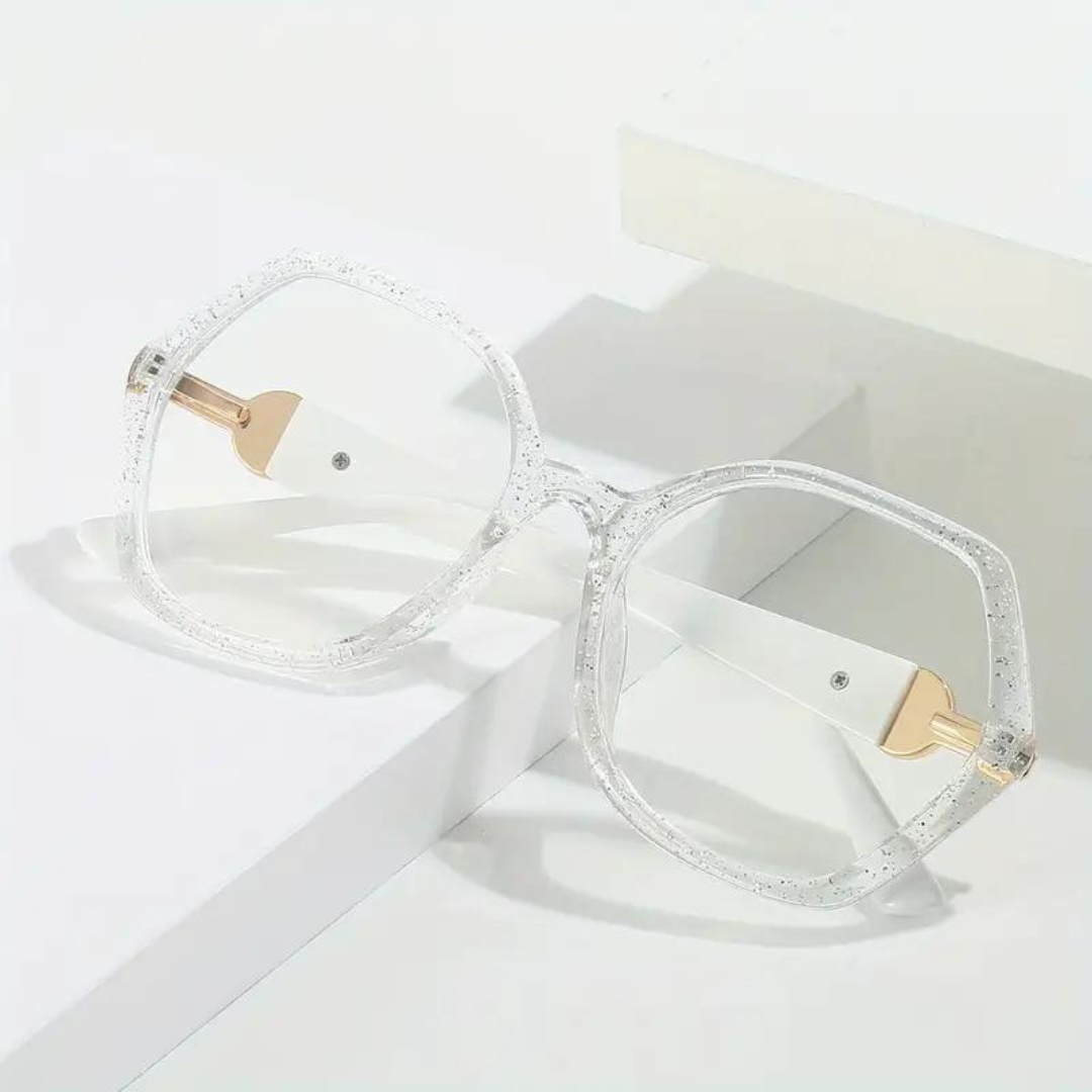 Diamond-cut transparent computer glasses resting on a white surface.