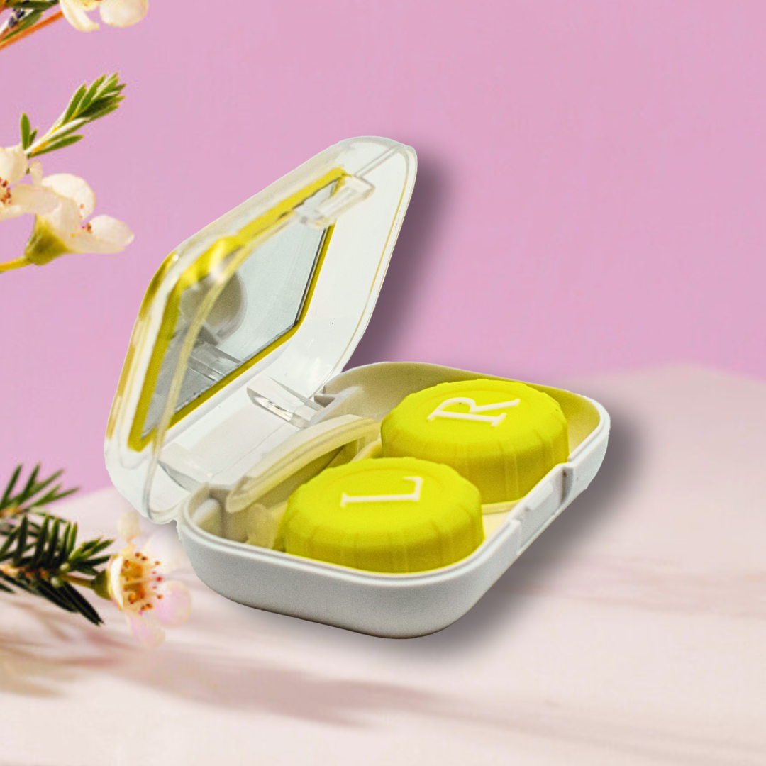 A lifestyle photo showing the First Lens Crystal Portable Contact Lens Case next to a pair of contact lenses, suggesting its practical use for on-the-go storage.